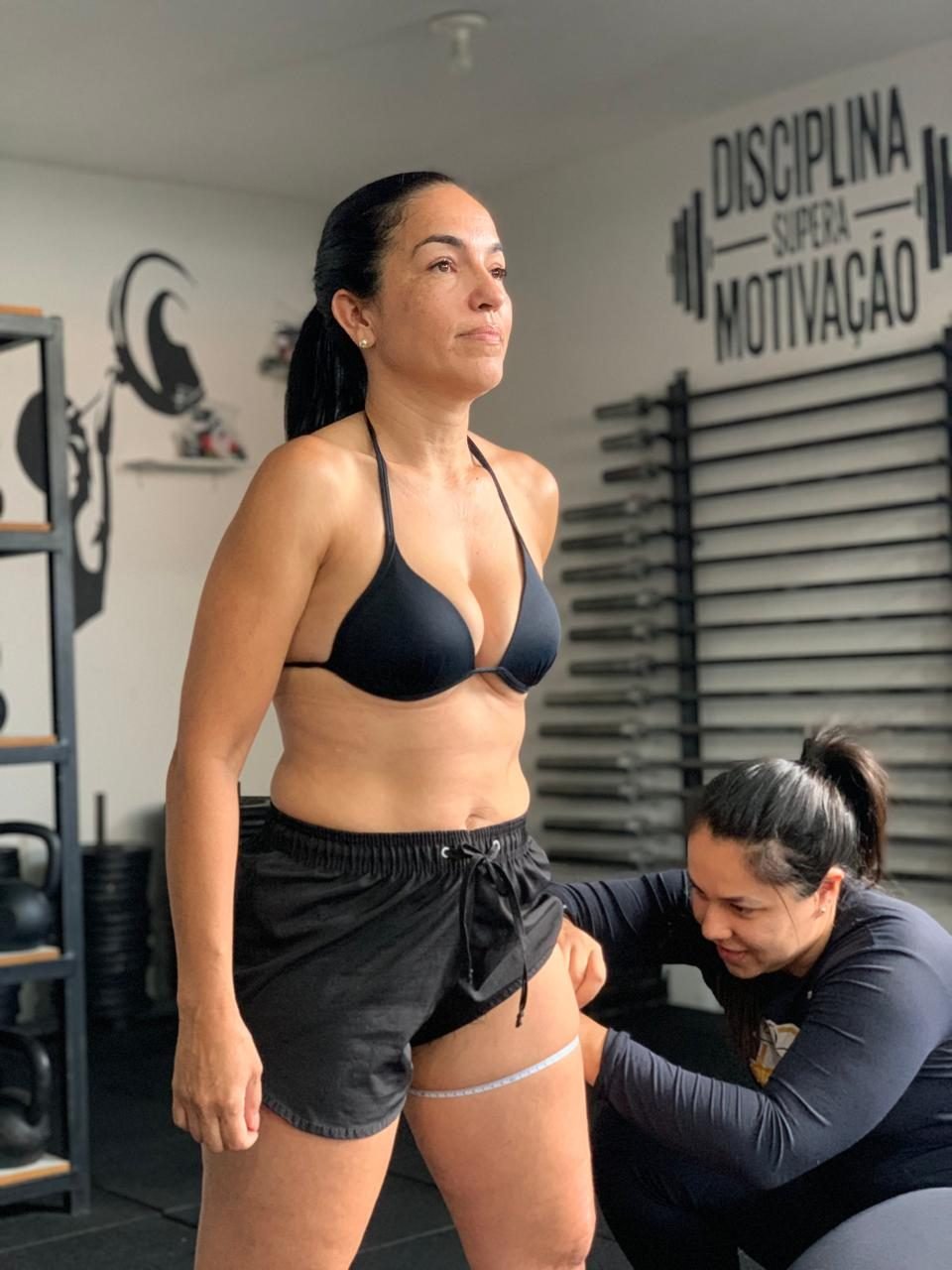 Professora medindo a coxa de uma aluna durante a avaliação física